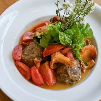 Meatballs with chanterelle mushrooms, tomatoes, and lettuce garnish