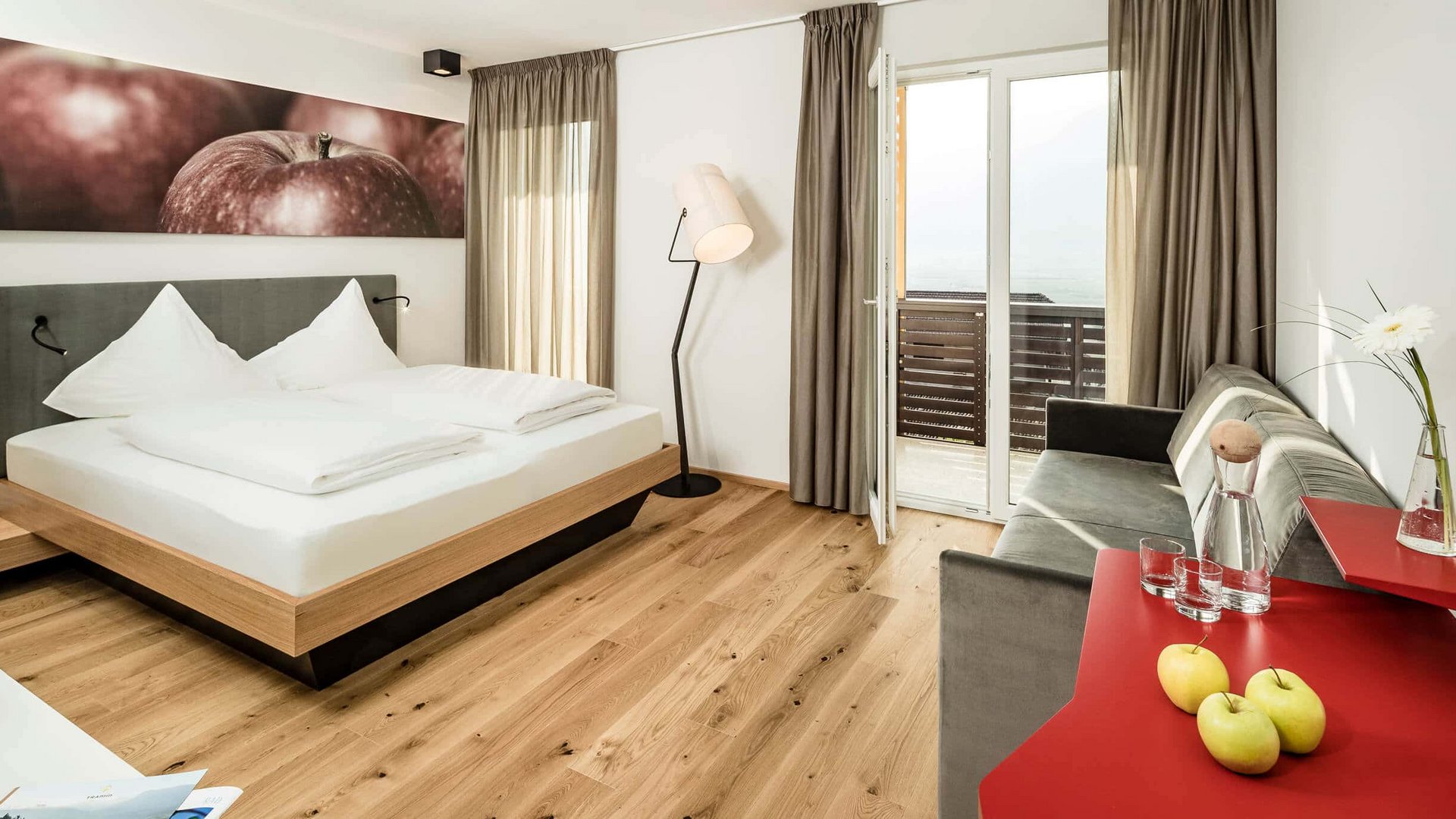 Modern bedroom with double bed, sofa, balcony, and wooden floor