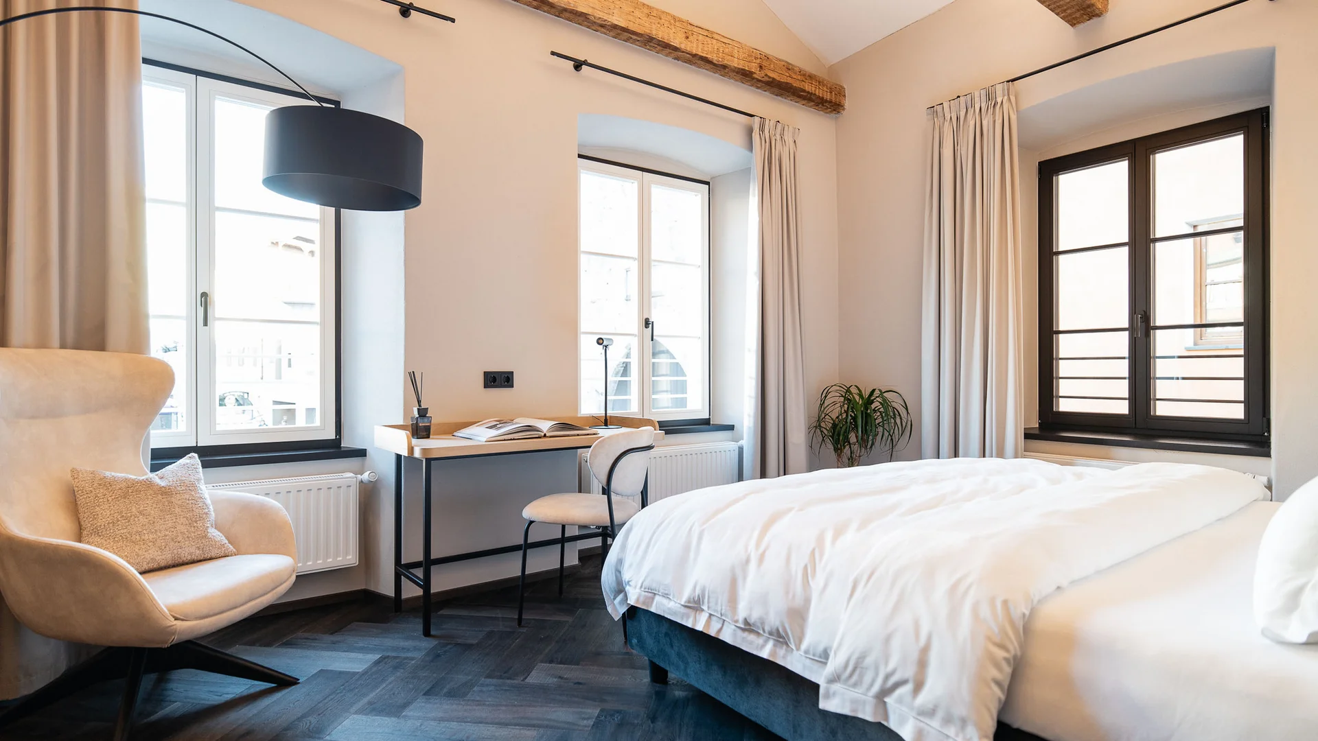 Lichte slaapkamer met houten balken, bureau en comfortabele stoel