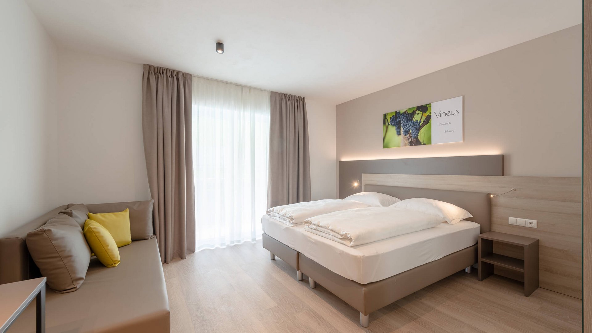 Modern hotel room with two single beds and sofa near window