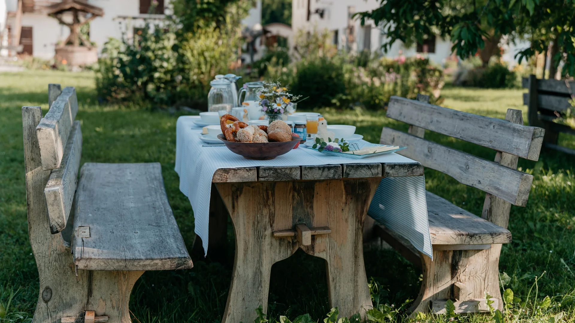 Rustikaler Holztisch mit Bänken im Garten mit gedecktem Frühstückstisch