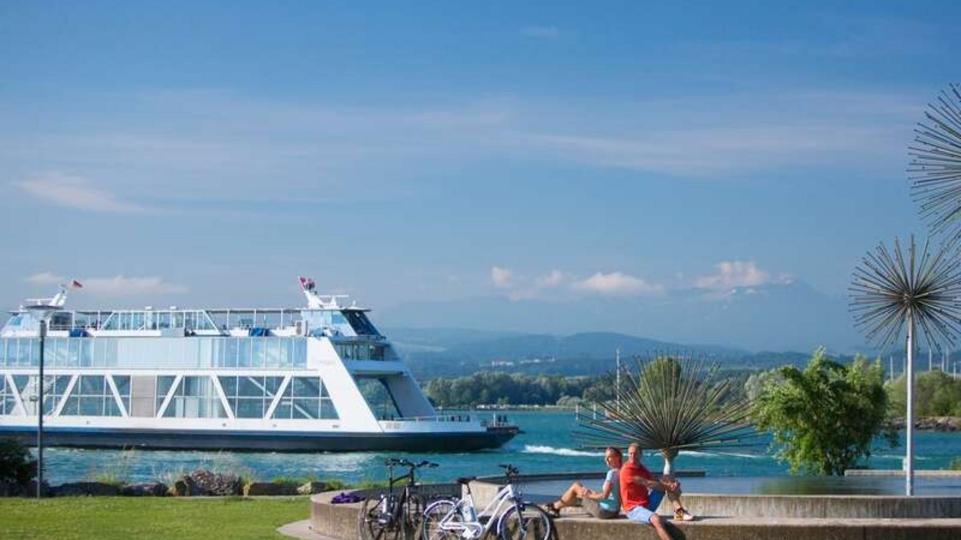 Ferry on the lake with two people and bicycles by the shore