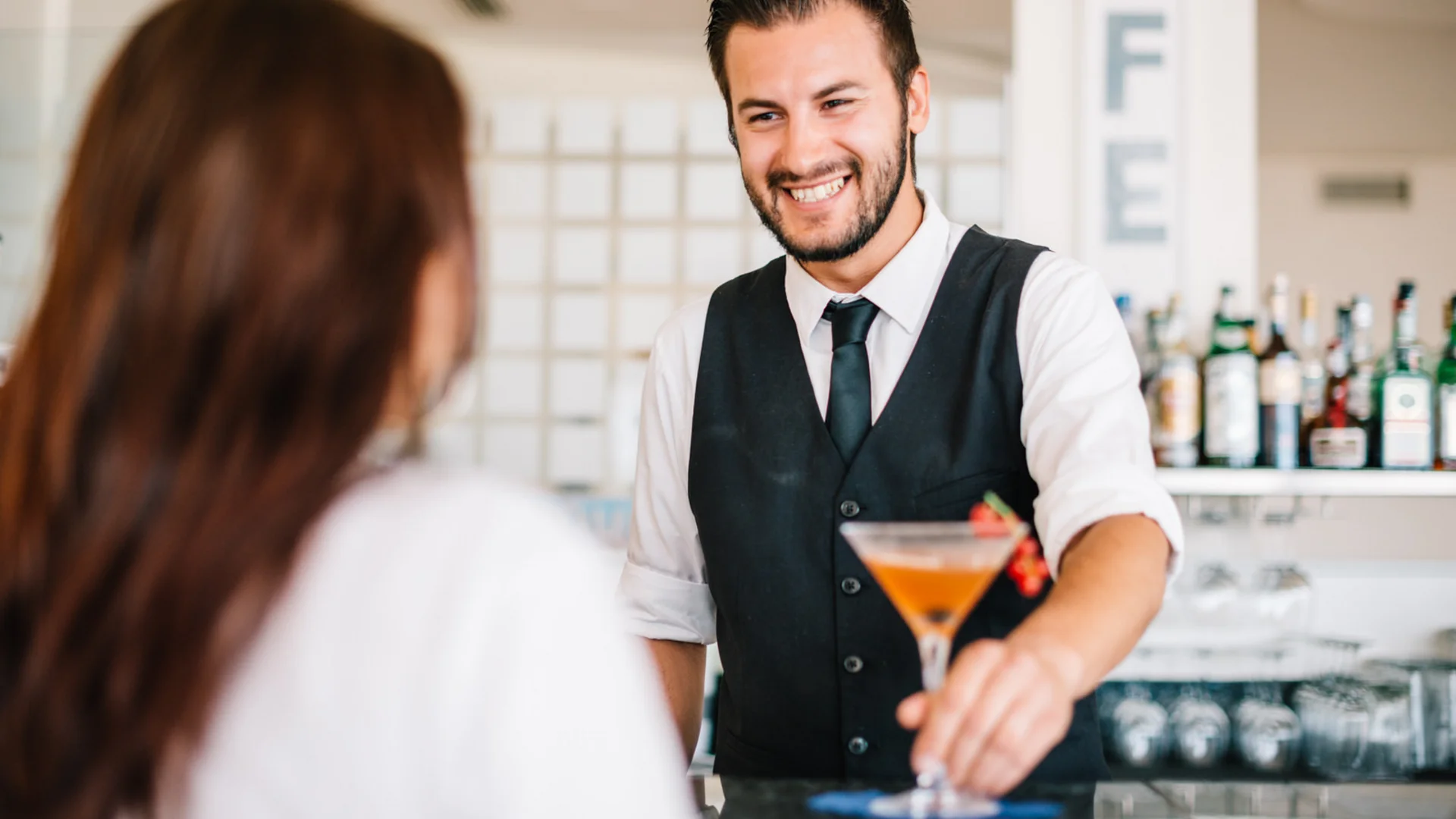 Bartender handing a cocktail to a woman with a smile