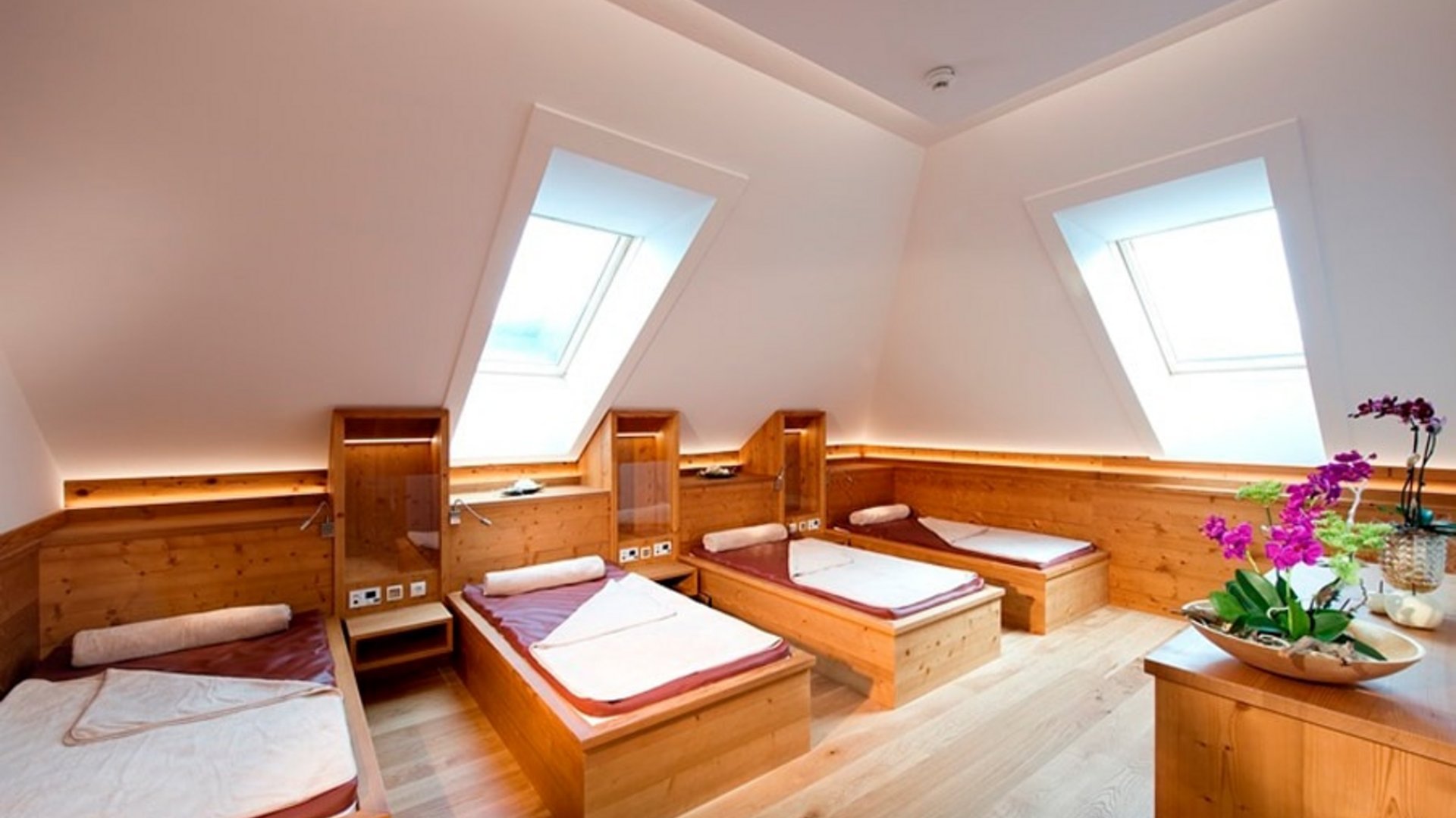 Bright room with four wooden single beds under skylights