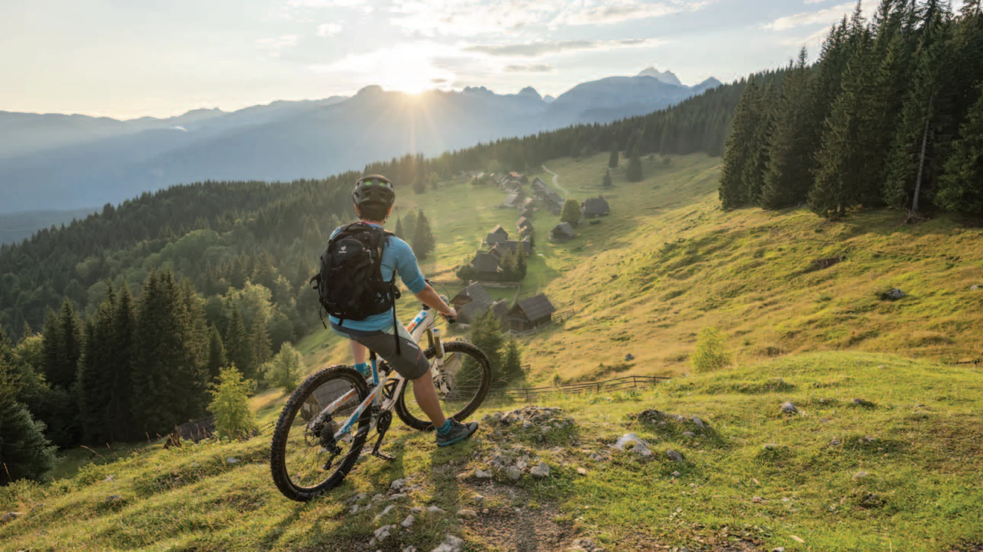 Mountainbiker kijkt naar Alpen dorp bij zonsondergang