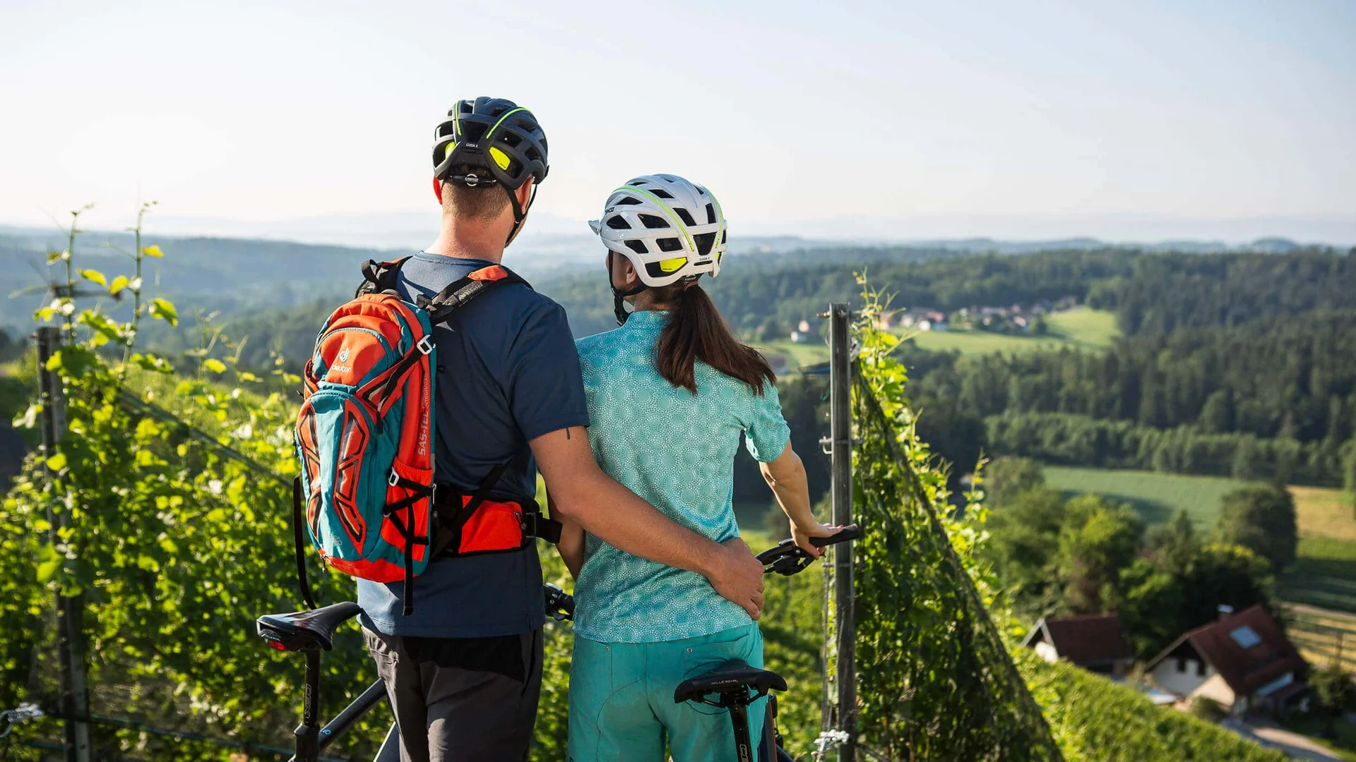 Paar mit Fahrrädern blickt auf grüne Landschaft und Häuser