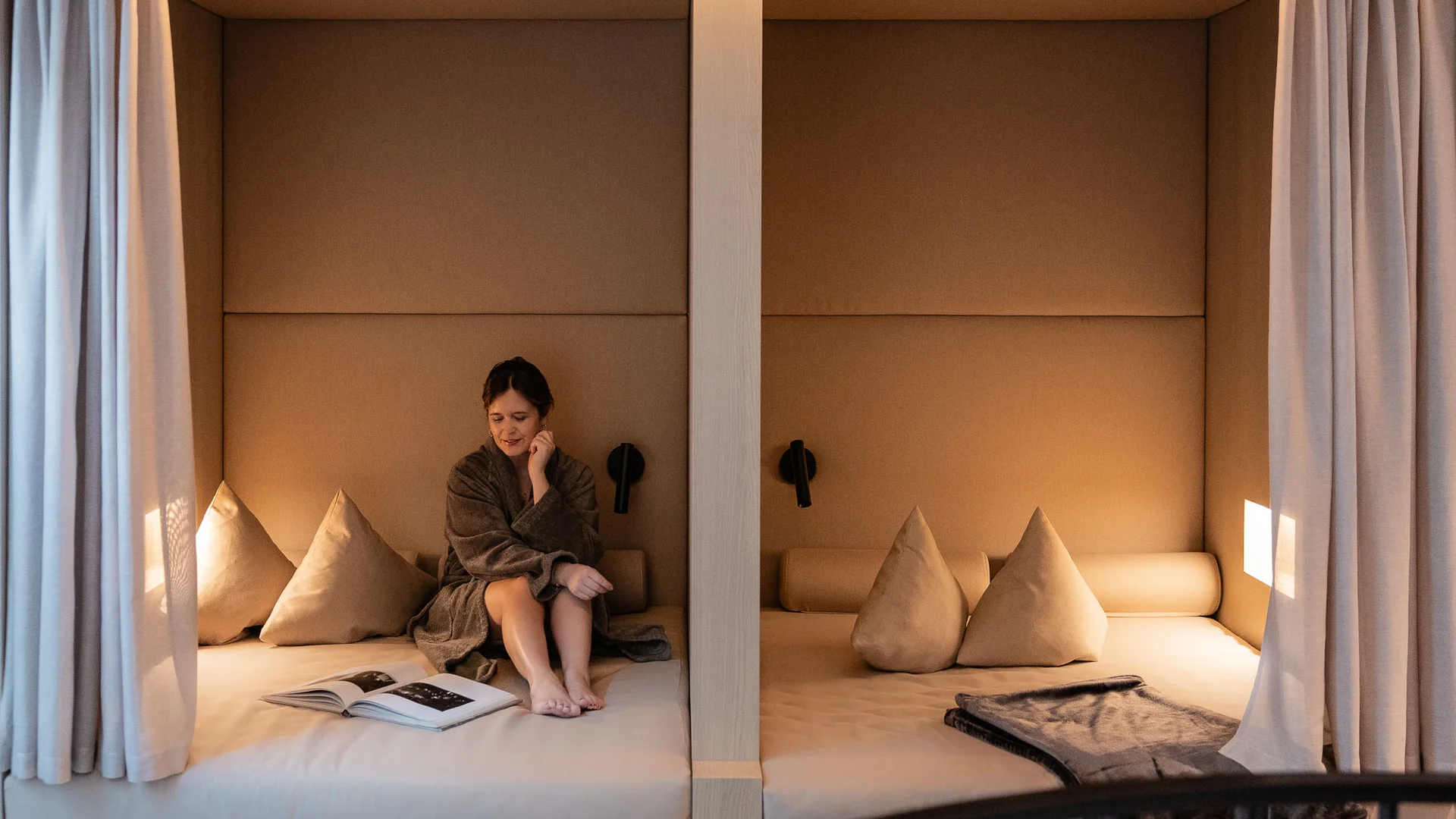 Vrouw in badjas zittend op gezellige bank in moderne kamer met gordijnen