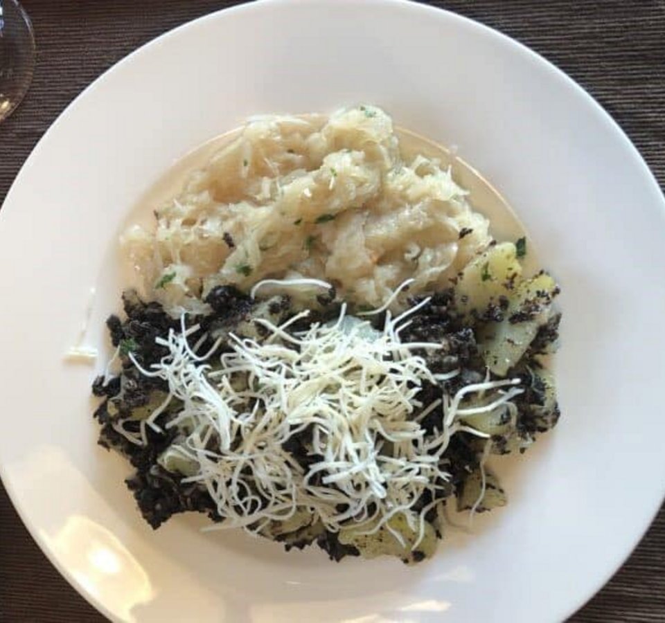 Plate with potatoes, black topping, and shredded cheese
