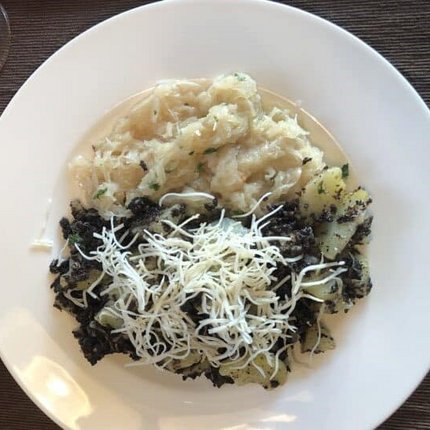 Plate with potatoes, black topping, and shredded cheese