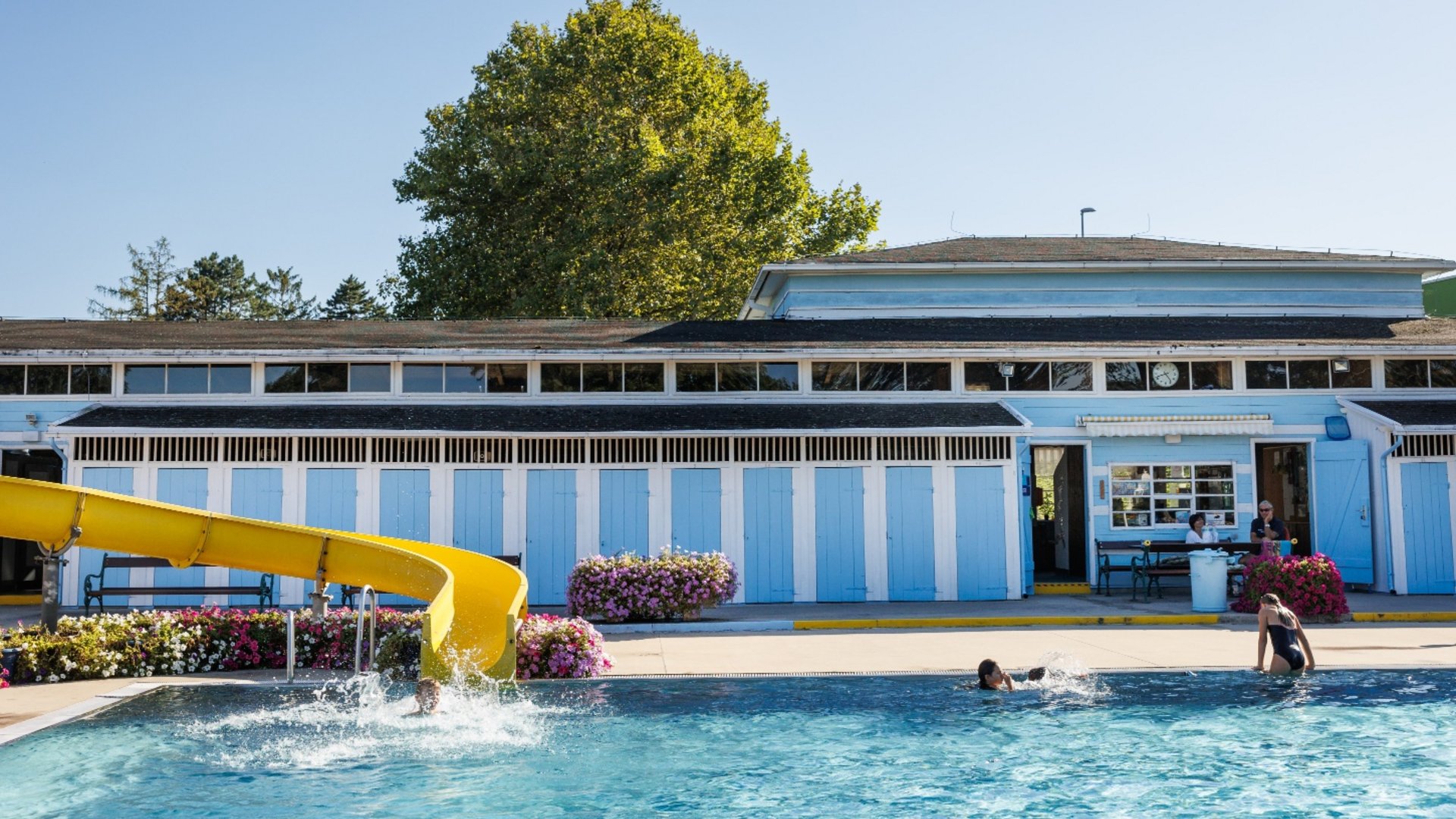 Swimming pool with yellow slide and blue and white changing rooms