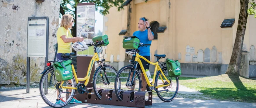 Dolomites - Trieste © FunActive Tours Two people with yellow rental bikes at an outdoor information board
