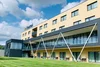 Collective enquiries Modern hotel building with green lawn and blue sky