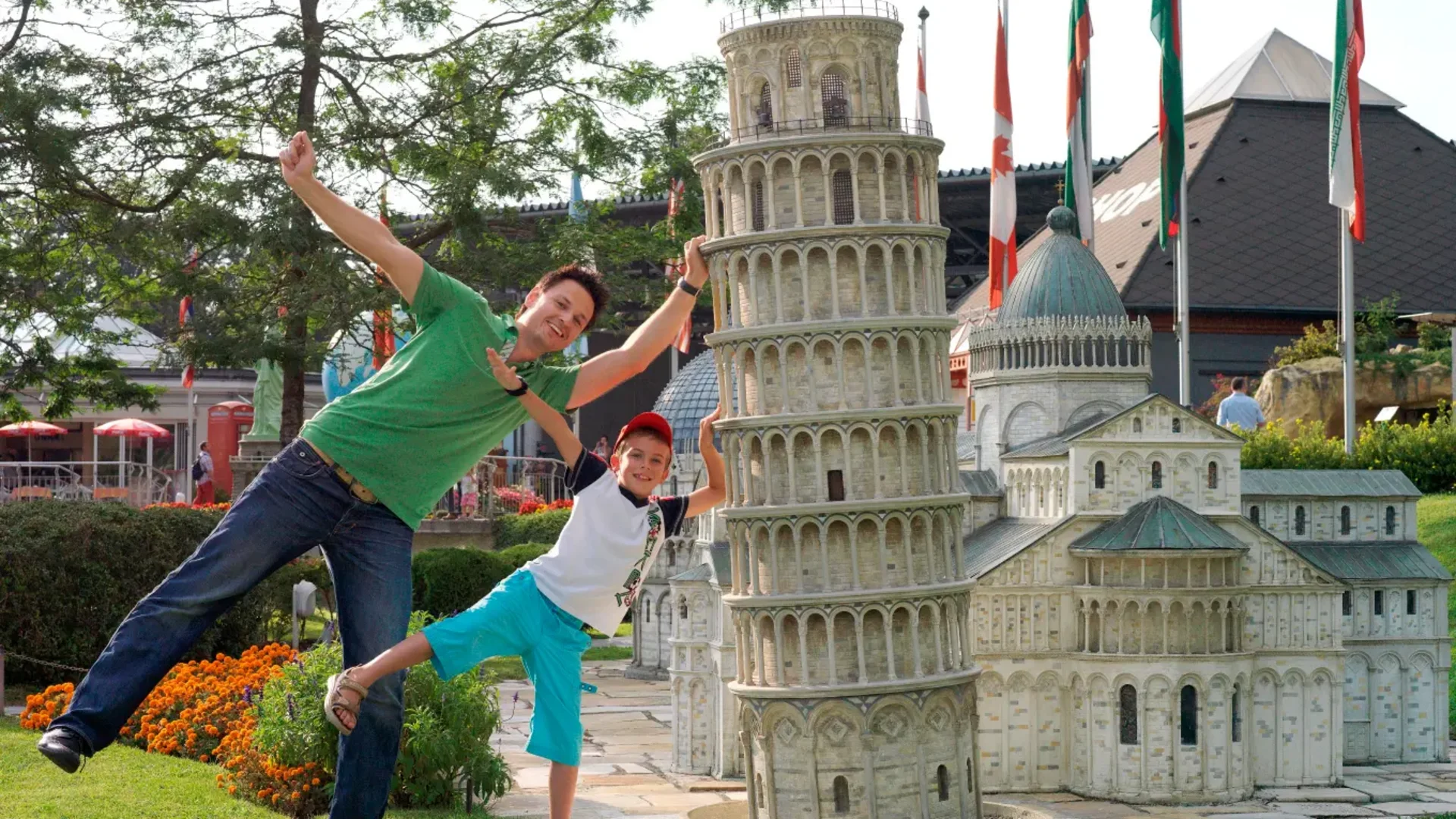 Vader en zoon poseren bij miniatuur van de scheve toren van Pisa
