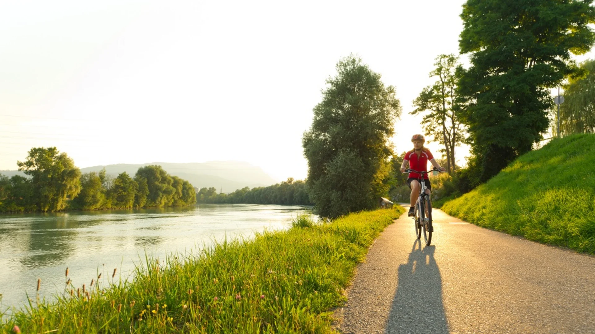 Fietser fietst op pad langs rivier bij zonsondergang