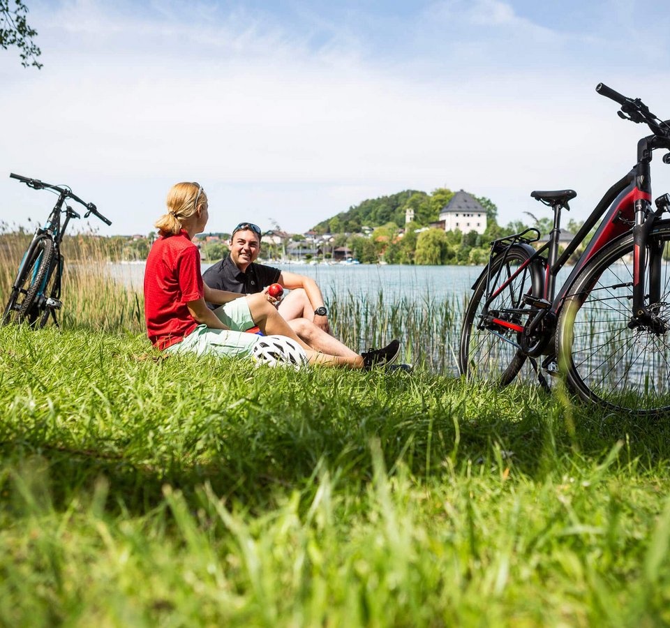 Zwei Radfahrer entspannen am Seeufer mit ihren Fahrrädern im Gras
