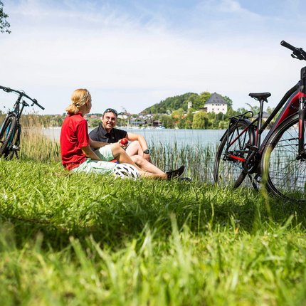 Zwei Radfahrer entspannen am Seeufer mit ihren Fahrrädern im Gras