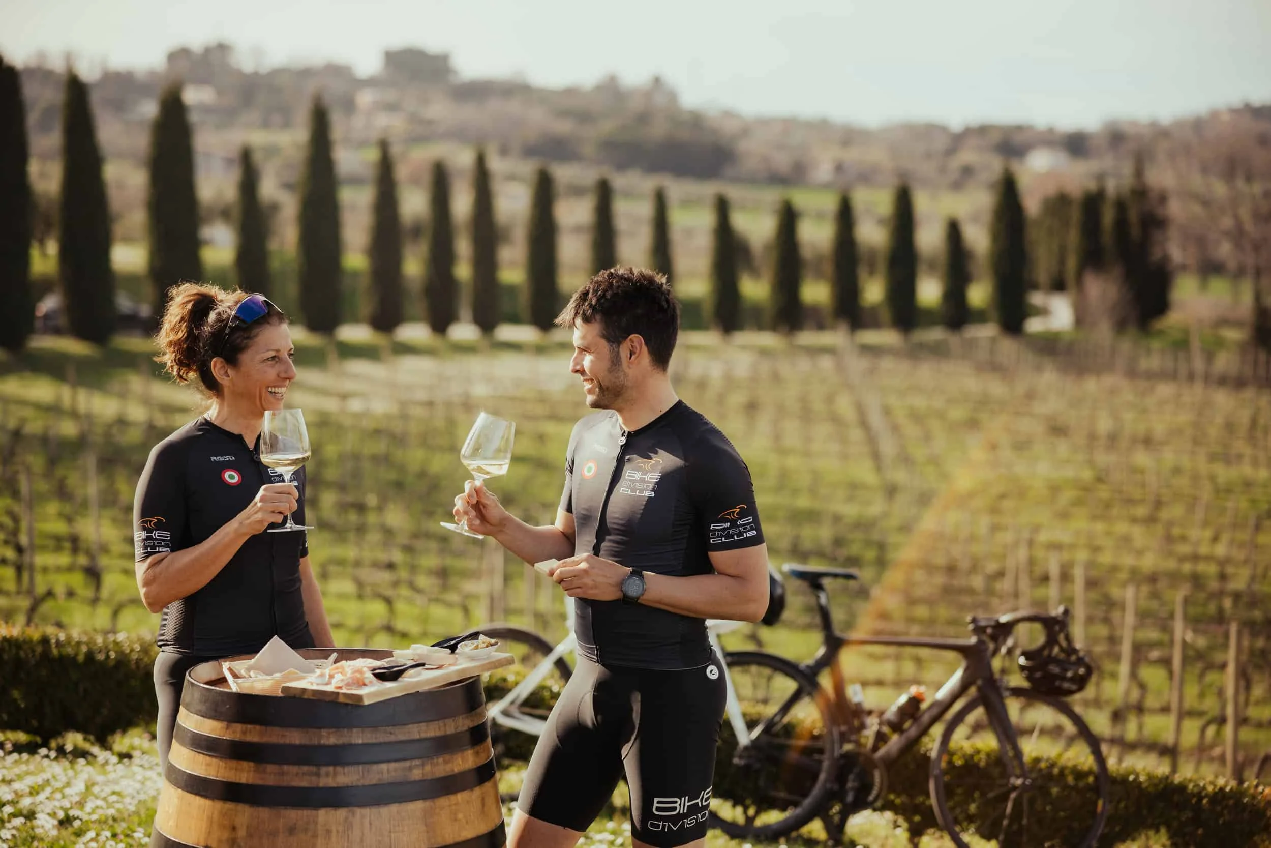 Accommodations Two cyclists drinking wine in vineyard on a sunny day