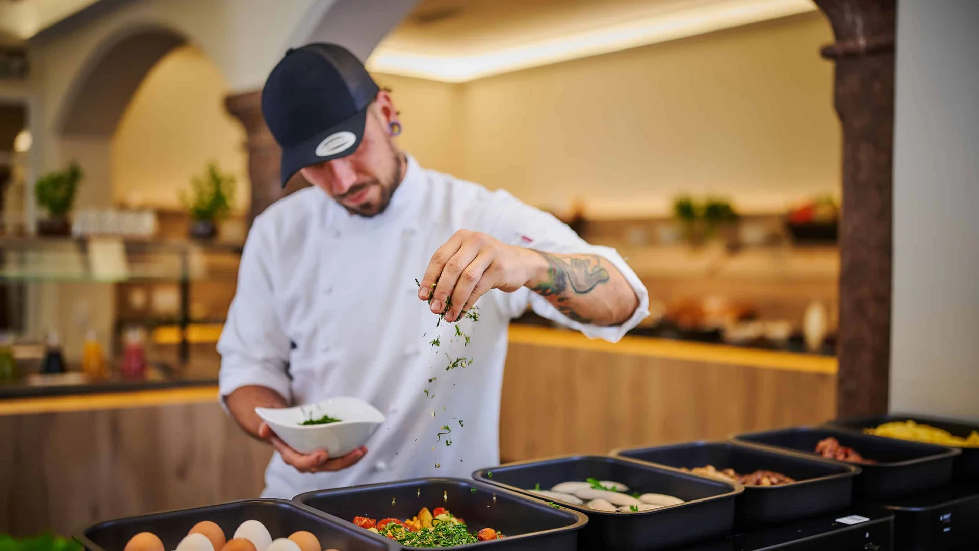 Chef seasoning food with fresh herbs in a restaurant kitchen