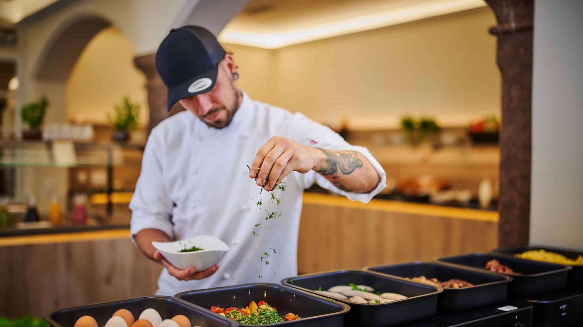 Chef seasoning food with fresh herbs in a restaurant kitchen
