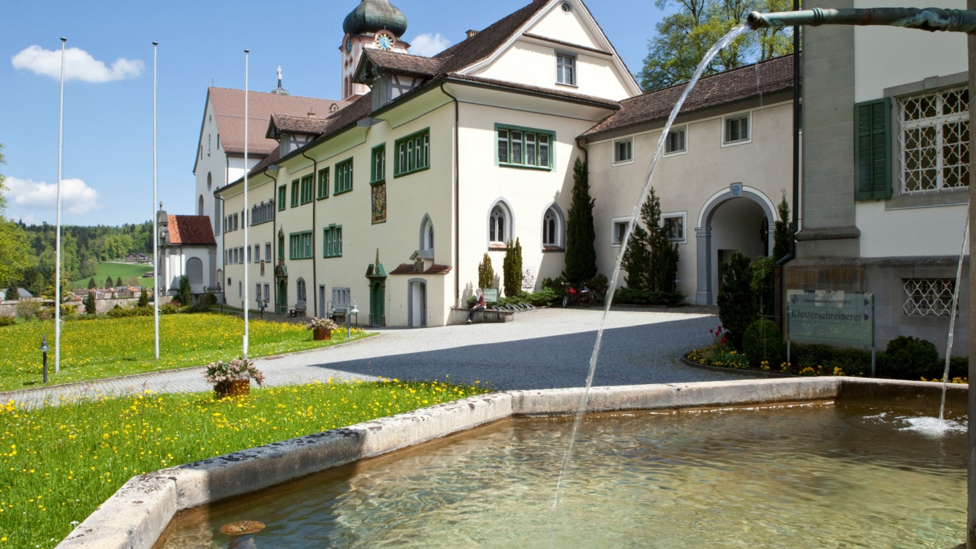 Fountain in front of historic monastery building on a sunny day
