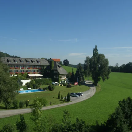 Hotel in grüner Landschaft mit Pool und Parkplätzen