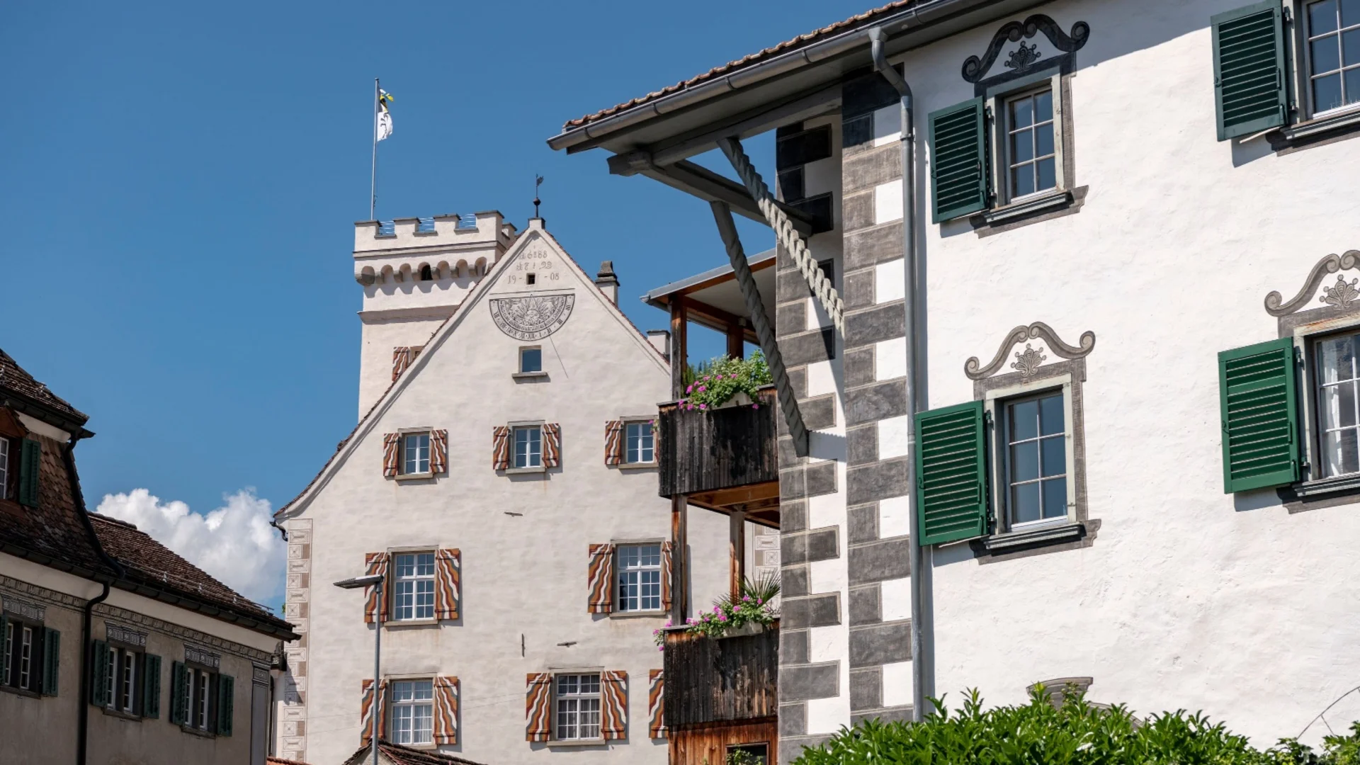 Historische Gebäude mit weißen Wänden und grünen Fensterläden unter blauem Himmel