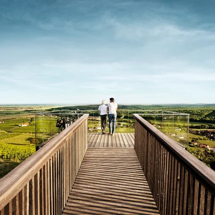 Zwei Personen auf Aussichtsplattform mit Blick auf grüne Landschaft und Dörfer
