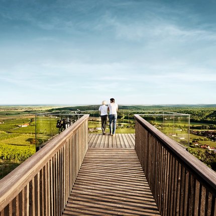 Two people on observation deck overlooking green fields and villages