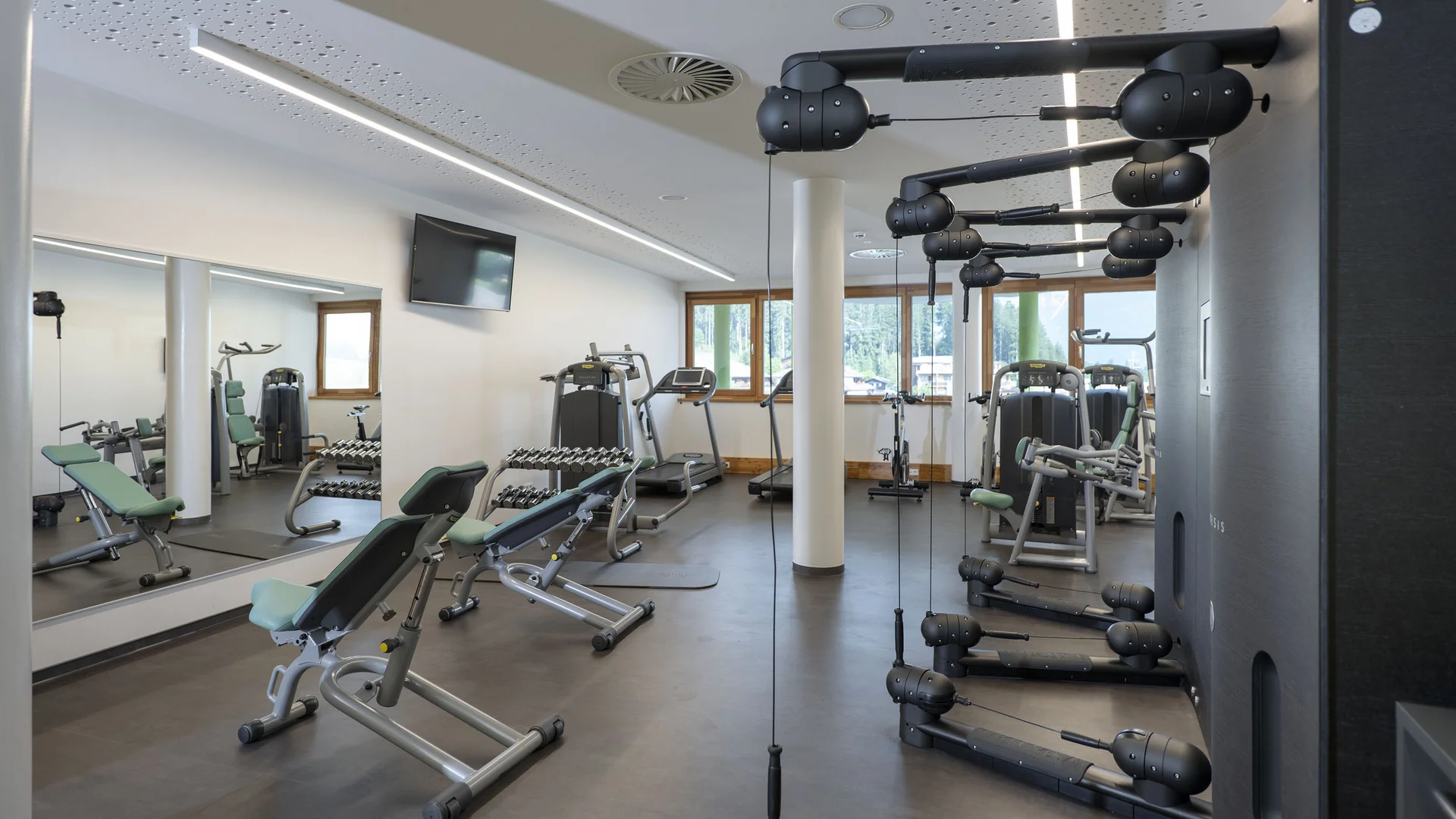 Fitnessraum mit verschiedenen Trainingsgeräten und Spiegeln
