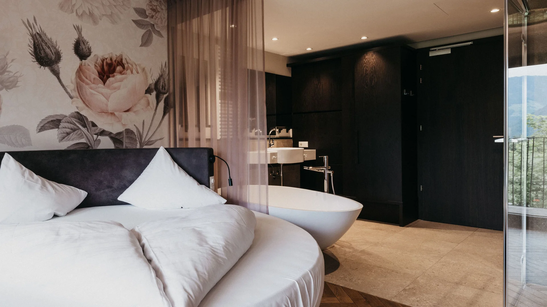 Modernes Hotelzimmer mit rundem Bett und freistehender Badewanne
