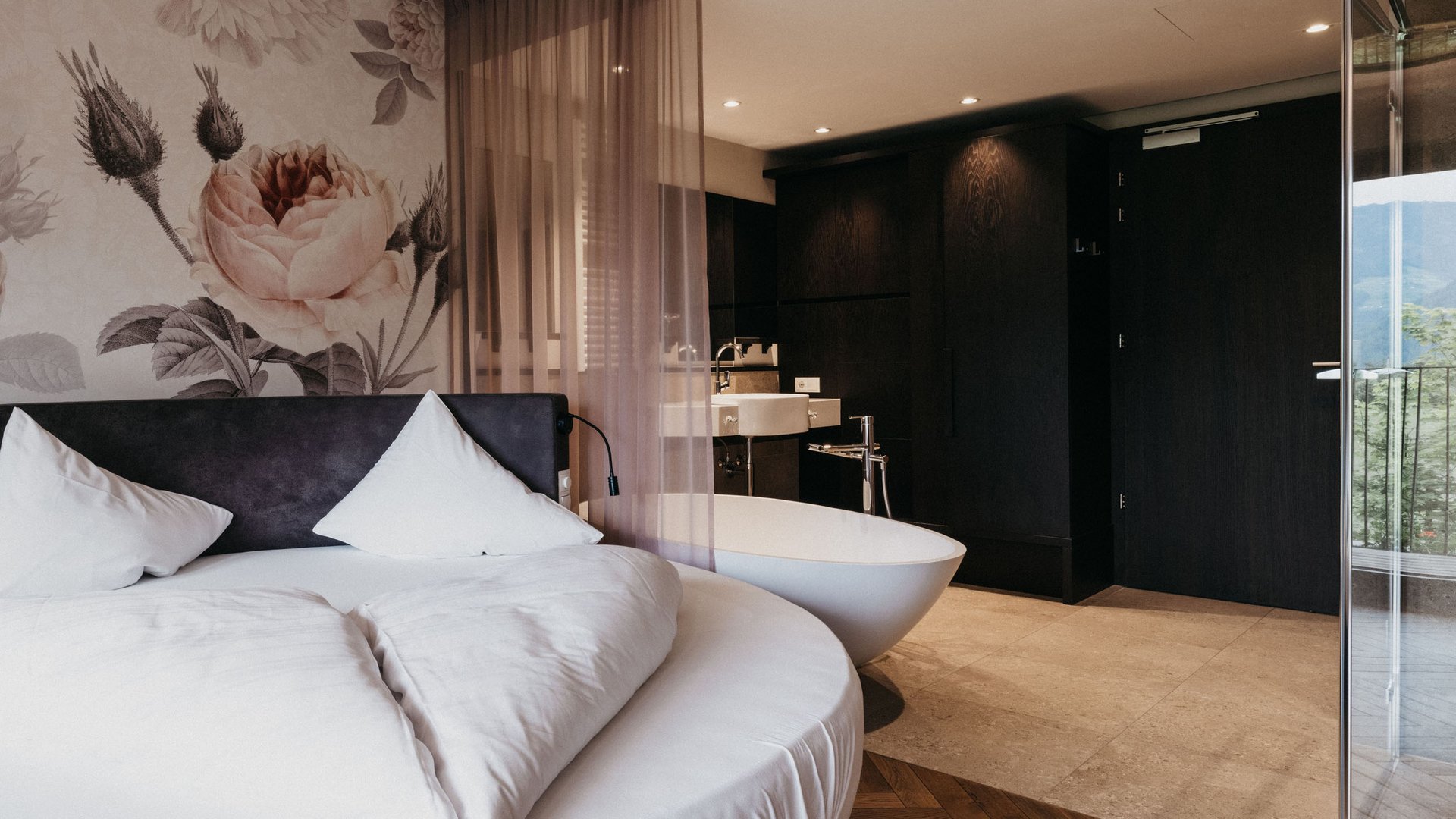 Modern hotel room with round bed and freestanding bathtub