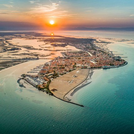 Luftaufnahme einer Küstenstadt bei Sonnenuntergang mit Wasser und Sandstränden