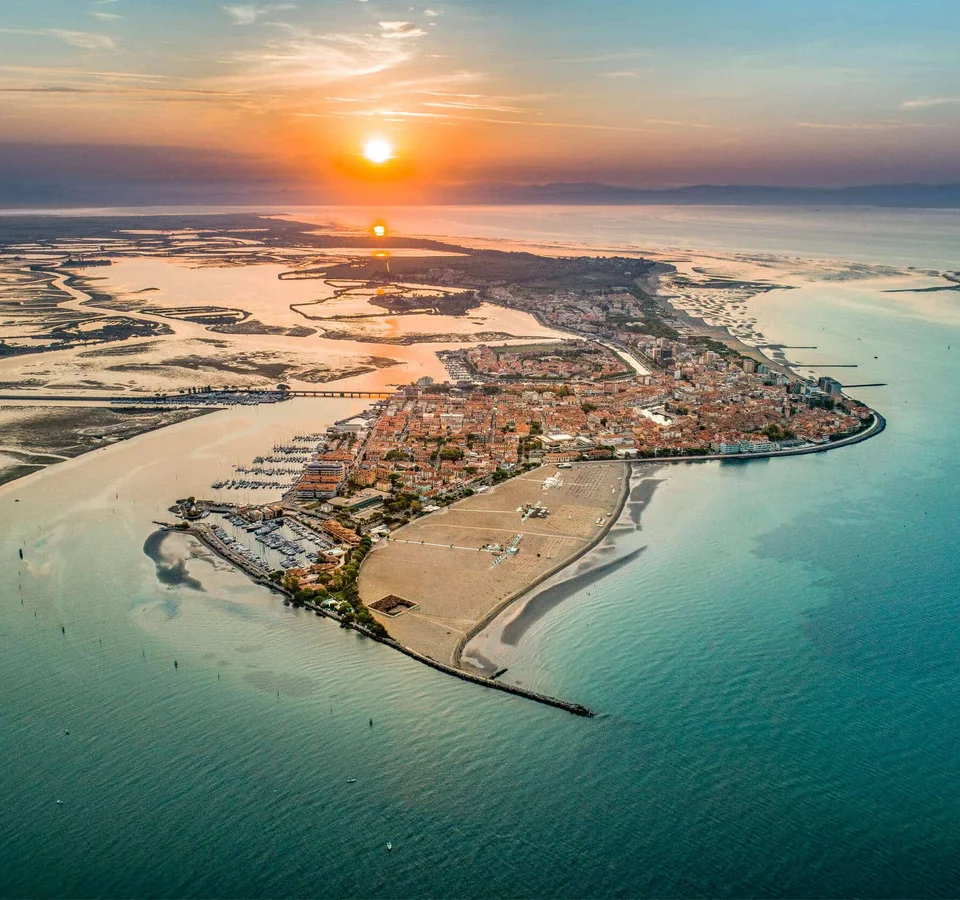 Luftaufnahme einer Küstenstadt bei Sonnenuntergang mit Wasser und Sandstränden