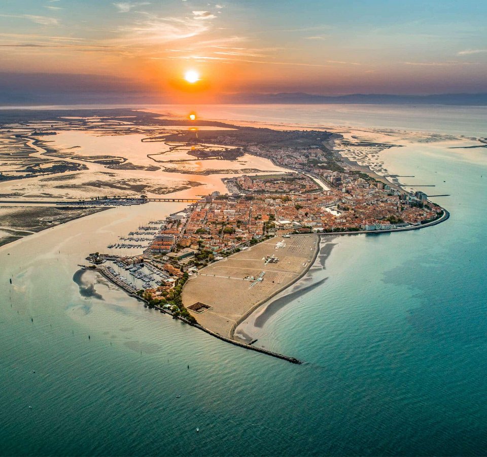 Luftaufnahme einer Küstenstadt bei Sonnenuntergang mit Wasser und Sandstränden