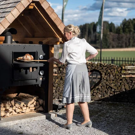 Vrouw bakt brood in houtgestookte oven buiten