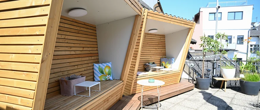Moderne houten zitplaatsen met kussens op zonnig terras