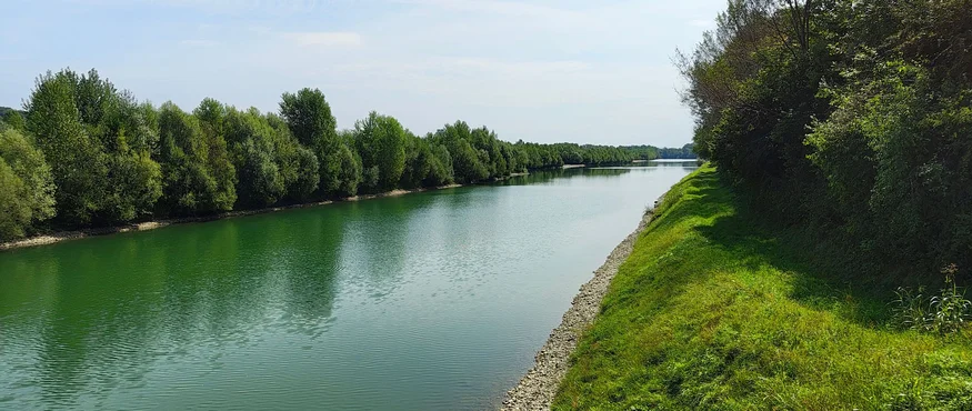 Rivier met groene oevers en bomen onder een blauwe lucht