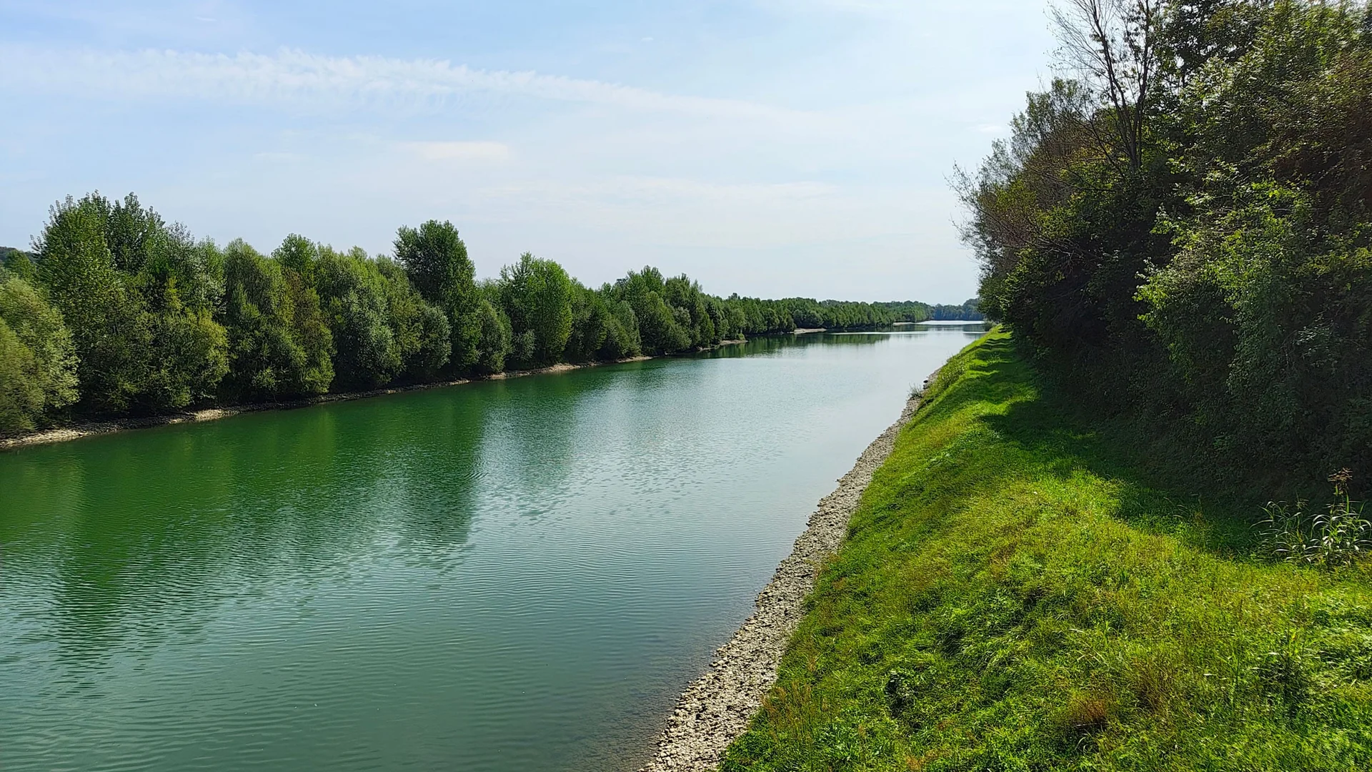 Rivier met groene oevers en bomen onder een blauwe lucht