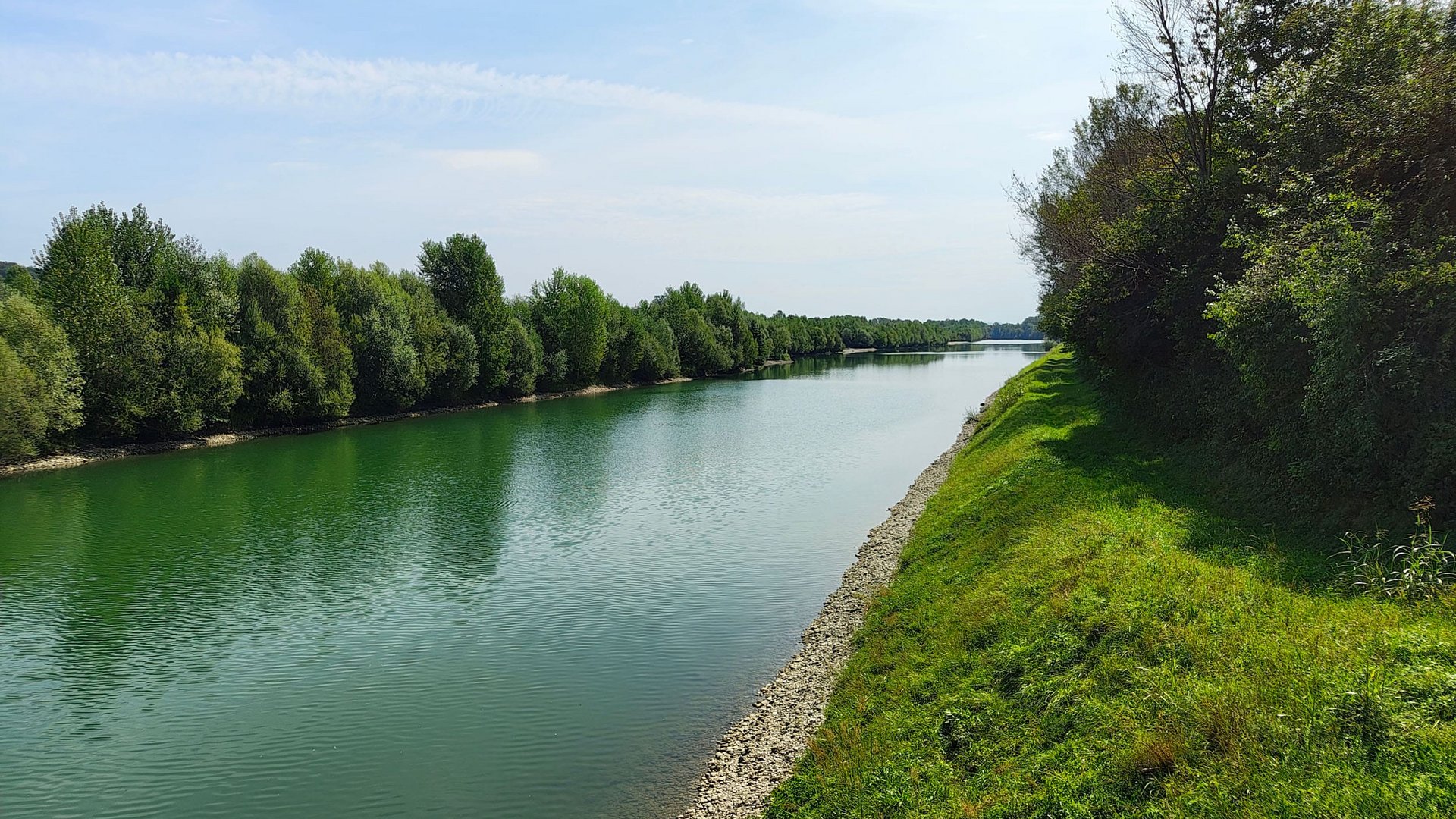 River with green banks and trees under a blue sky