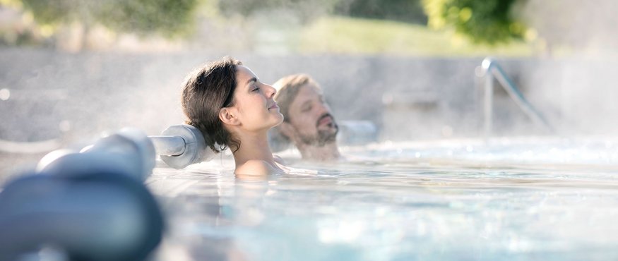 Zwei entspannte Personen in einem Whirlpool im Freien