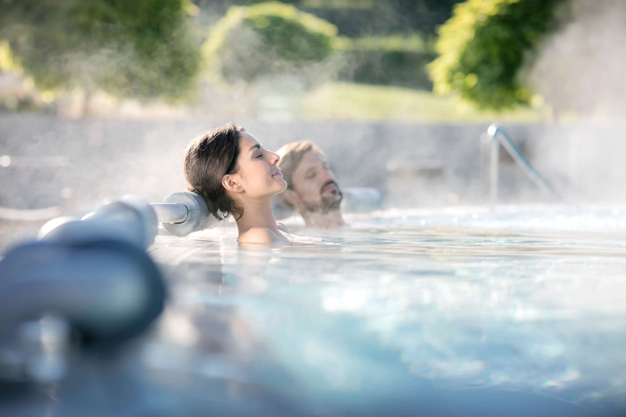 Zwei entspannte Personen in einem Whirlpool im Freien