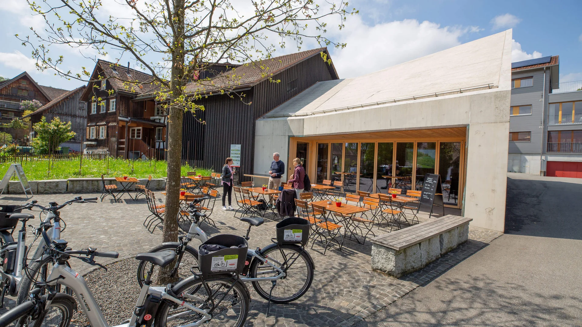 Buitenzitplaatsen van café met tafels, stoelen en fietsen op een zonnige dag