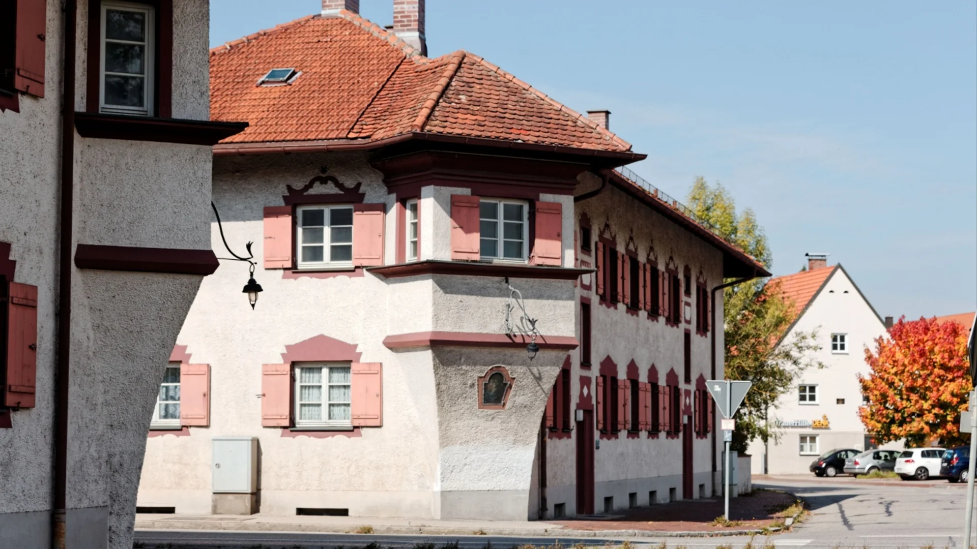 Traditionelles deutsches Haus mit roten Fensterläden und Ziegeldach an einer ruhigen Straße