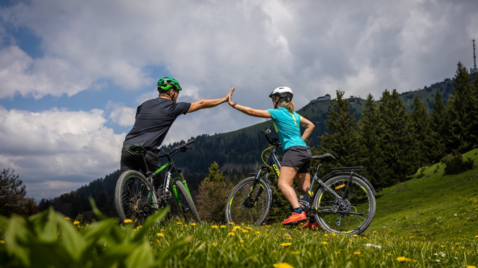 Two cyclists giving a high five on a mountain meadow