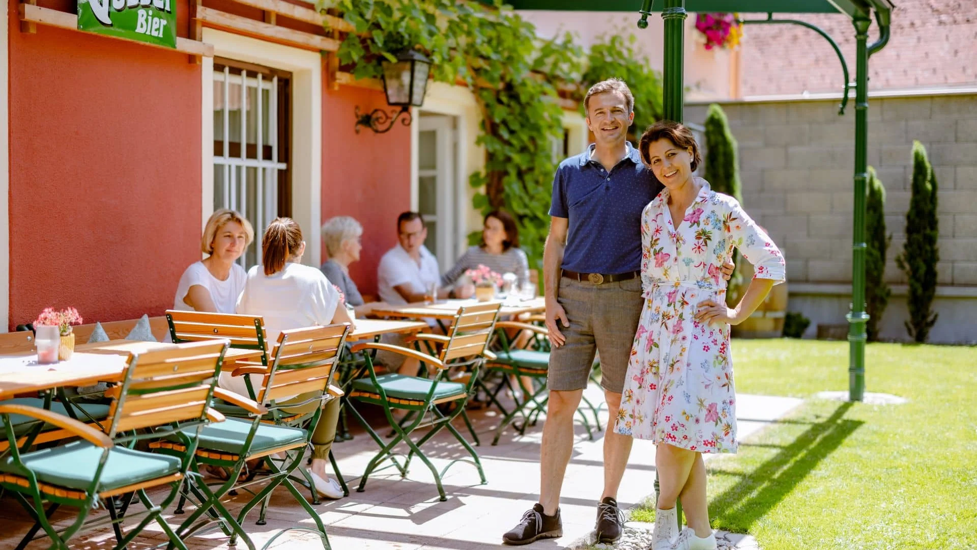 Toeristen genieten van zonnige pauze in biergarten met Gösser Bier bord