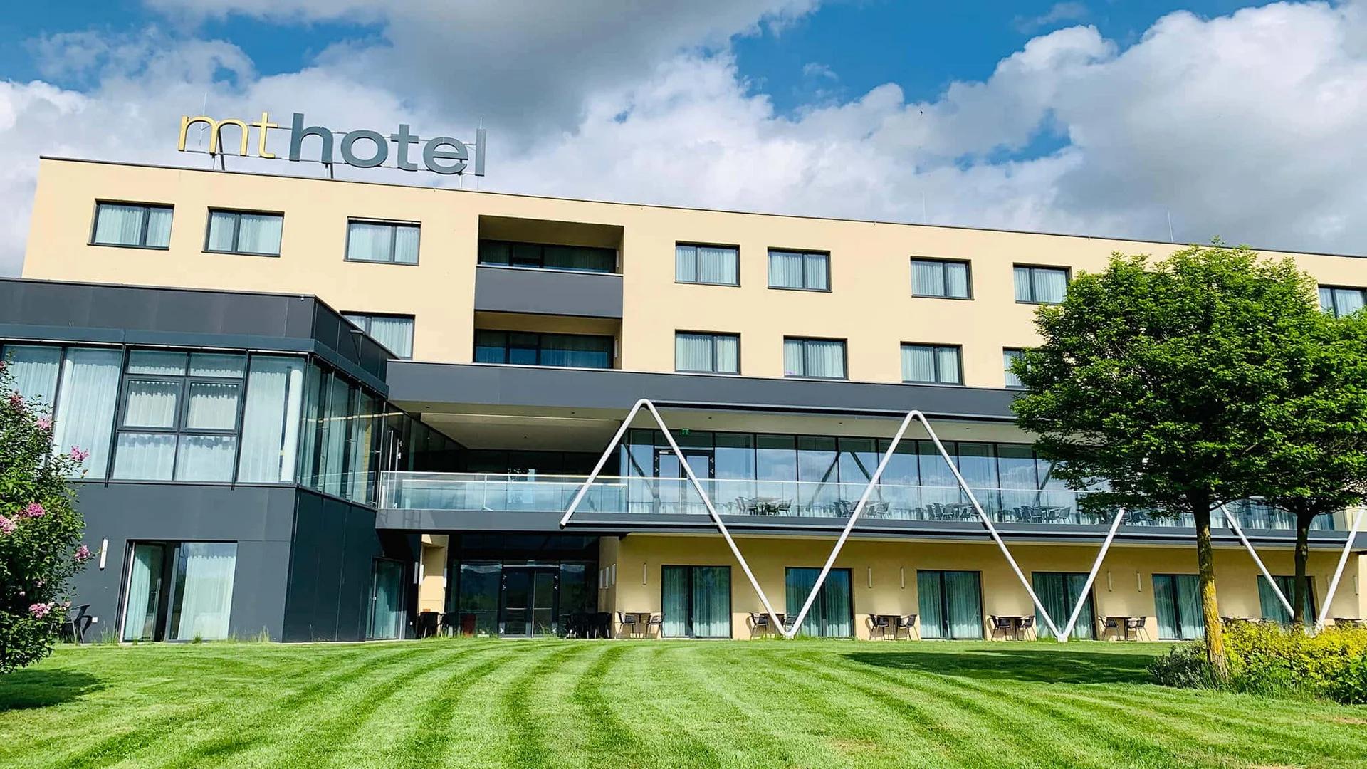 Modern hotelgebouw met groen gras en blauwe lucht