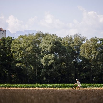Two cyclists riding on a path with forest and a castle in the background