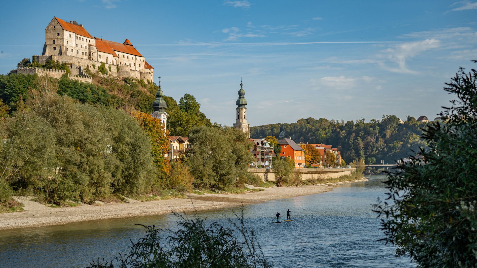 Castle and church towers by river with people stand-up paddleboarding