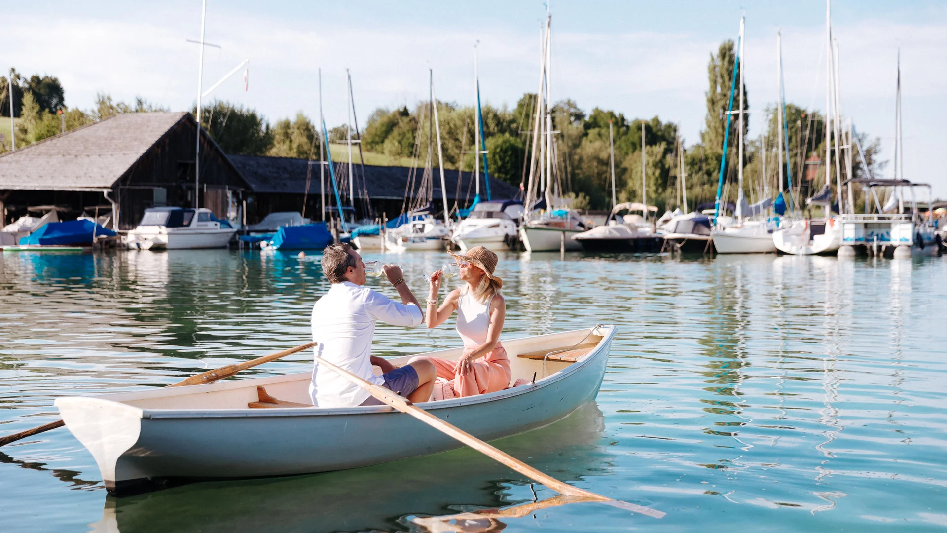 Couple drinking prosecco in rowboat at sunny marina