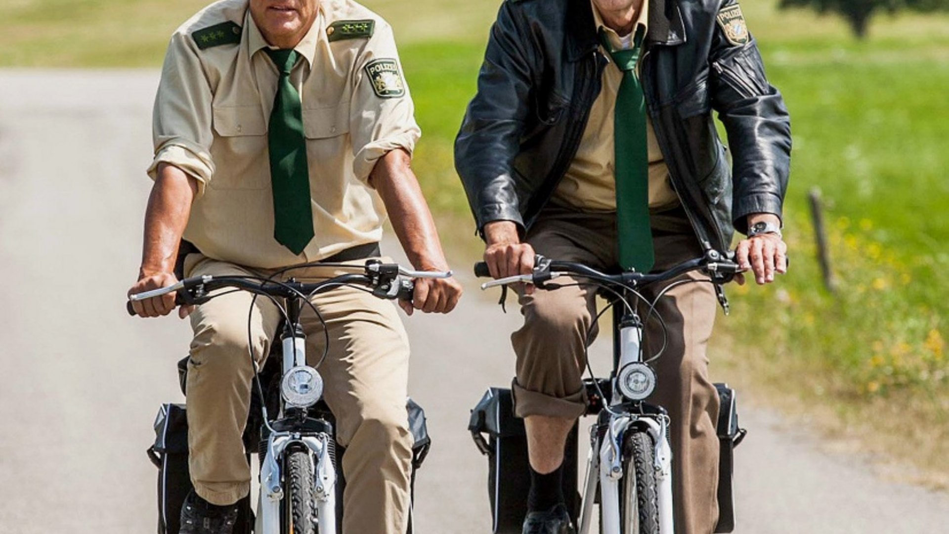 Two police officers riding bicycles on a country road